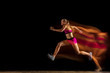 © master1305 - Professional female relay racer training isolated on black studio background in mixed light. Woman in sportsuit practicing in running. Healthy lifestyle, sport, workout, motion, action concept.
