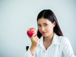 © Apichet - Close up pretty woman biting an apple for diet with happy in office isolated over white background. Eating and health concept.