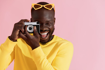 Wall Mural - Happy man photographer with photo camera on colorful background