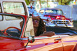 girl driving old orange car in Havana, Cuba
