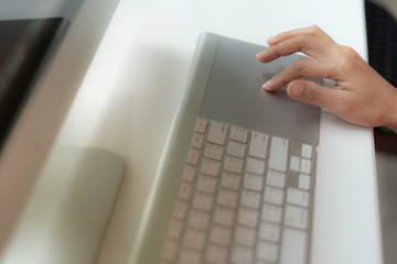 Hands of woman typing on the white modern keyboard or using computer playing social media in coffee shop.