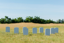 Tombstones On Green Grass And Blue Sky In Graveyard