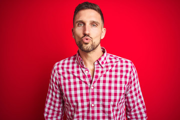 Sticker - Young handsome man over red isolated background looking at the camera blowing a kiss on air being lovely and sexy. Love expression.