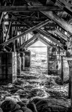 Black And White Structure Under Pier With Ocean And Rocks