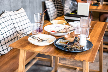 Dirty dishes of leftover food on table in restaurant.