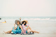 © grooveriderz - Two Women enjoying beach relaxing joyful in summer by tropical blue water.Model on travel wearing beach hat.