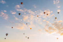 Many Hot Air Balloons Flying Against Sunny Sundown Sky During Festival In Cappadocia