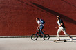 © Manuel Ruiz Alba/ADDICTIVE STOCK - Side view of young black successful male friends in casual apparel and stylish sunglasses riding bike and skateboard