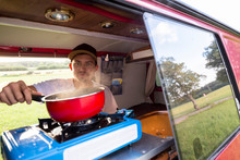 Holzgerlingen, Baden-W¸rttemberg, Germany: A Man Cooking Rice On A Gas Stove In His Red Volkswagen Multivan (T4) Campervan.