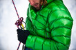 © Tandem Stock - Midsection of man in puffer jacket holding safety harness