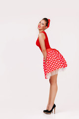 smiling pin up woman in polka dot red dress isolated on gray background. cute girl posing in retro style