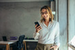 © Jacob Lund - Smiling businesswoman using phone in office