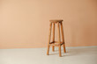 Round wooden stool with beige wall background interior