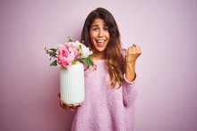 Young Beautiful Woman Holding A Pot Of Flowers Over Pink Isolated Background Screaming Proud And Celebrating Victory And Success Very Excited, Cheering Emotion