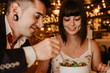 © Alberto Menendez/ADDICTIVE STOCK - Cheerful young man and woman eating tasty fresh salad while sitting at table on blurred background of luxury restaurant during romantic dinner
