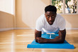 © twinsterphoto - Young African American man doing a plank exercise at gym. Male fitness model with serous and determined face