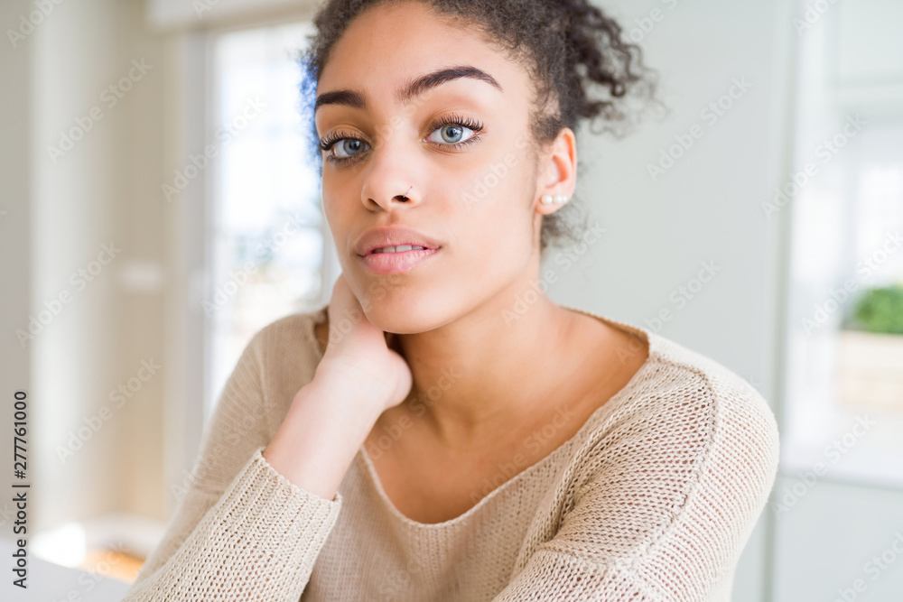 Beautiful young african american woman with blue eyes relaxing at home ...