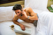 © theartofphoto - Handsome shirtless muscular young man in bed talking on cell phone placing a call