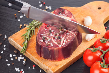 meat steak and cooking ingredients on black background