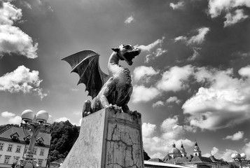 Canvas Print - The Dragon statues at the Dragon Bridge and Cathedral of St. Nicholas at the background in center of Ljubljana, Slovenia