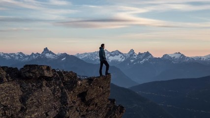 Wall Mural - Adventurous man is standing on top of the mountain and enjoying the beautiful view during a vibrant sunset. Taken on top of Cheam Peak in Chilliwack, East of Vancouver, BC, Canada. Animation