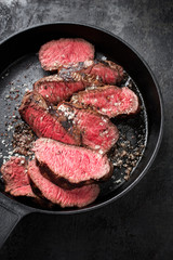 Wall Mural - Barbecue dry aged wagyu sirloin beef steak sliced with salt and pepper as top view on a gray cast iron design pan