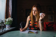 © Kike Arnaiz/ADDICTIVE STOCK - Adult woman thinking while sitting at table in cozy room and writing in notebook