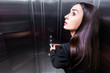scared businesswoman, suffering from claustrophobia, looking up while pushing button in elevator