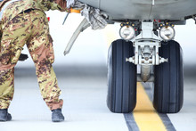 An Army Mechanic Is Inspecting The Landing Gear Of A Military Cargo Plane.