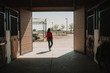 © Sonia Almudevar/ADDICTIVE STOCK - Back view of woman walking out of horse stable on ranch in bright sunshine
