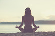 © Kitja - Young woman practicing yoga on the sandy beach.
