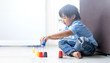 funny child playing with colourful cup toys on floor.Asian little boy playing stack cup at home