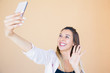 © Mangostar - Happy joyful lady posing for selfie, holding smartphone in outstretched hand and smiling. Happy young woman waving at cellphone screen in greeting gesture. Taking selfie concept