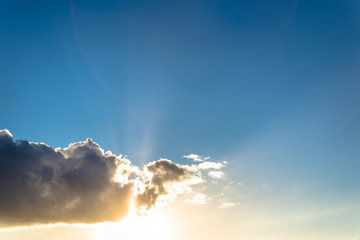 Wall Mural - Clouds and sun in a blue sky at sunset