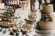 Delicious Candy Bar At Wedding Reception. White And Chocolate Desserts With Fruits, Macarons, Cake, Cupcakes On Stand, Modern Sweet Table At Wedding Or Baby Shower. Luxury Catering Concept