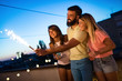 © NDABCREATIVITY - Group of friends enjoying rooftop party with sparklers
