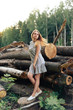 beautiful girl in a gray dress on the background of logs in the forest