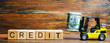 © Andrii Yalanskyi - Wooden blocks with the word Credit and forklift. Loan provided by the lender to the borrower at a certain interest for the use of money. Bank credits. Commerce, consumer, investment loans