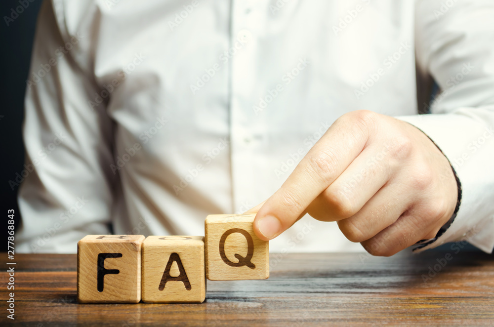 Businessman puts wooden blocks with the word FAQ (frequently asked questions). Collection of frequently asked questions on any topic and answers to them. Instructions and rules on Internet sites
