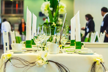 Christmas party dinner table setting with tableware and silverware and glasses set and Candlestick and flower in restaurant.