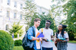 © Iryna - Three positive students from different coutries with books and backpacks talking while walking against building in university campus outdoor. New academic year concept.