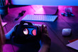 © insta_photos - Female hands hold 3d 360 vr headset glasses goggles at work table computer background in futuristic purple neon light, girl gamer virtual augmented ar reality innovative tech concept, close up view