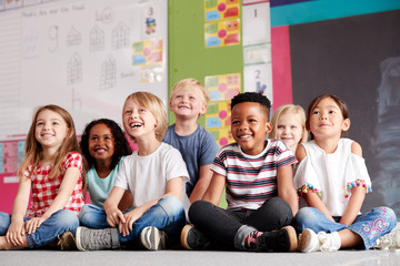 group of elementary school pupils sitting on floor in classroom