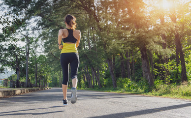 Wall Mural - Young fitness sport woman running on the road in the morning, Young fitness sportswoman runner running on tropical park trail. People and sport concept