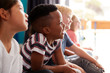 © Monkey Business - Group Of Elementary School Pupils Sitting On Floor Listening To Teacher