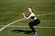 © Дмитрий Днепровский - Girl doing a squat at the stadium. Black leggings and top. Football field.