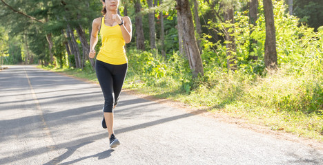 Wall Mural - Young fitness sport woman running on the road in the morning, Young fitness sportswoman runner running on tropical park trail. People and sport concept