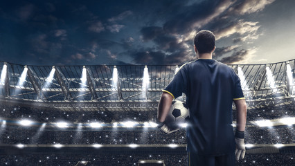 Wall Mural - soccer player standing with the ball against the crowded stadium on background