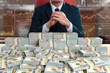 businessman sitting with pile of 100 dollar banknote