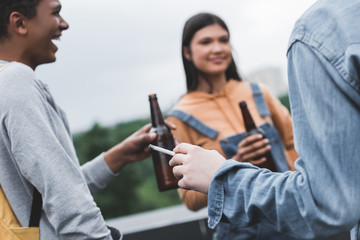 Wall Mural - selective focus of teenagers holding glass bottles with beer and smoking cigarette